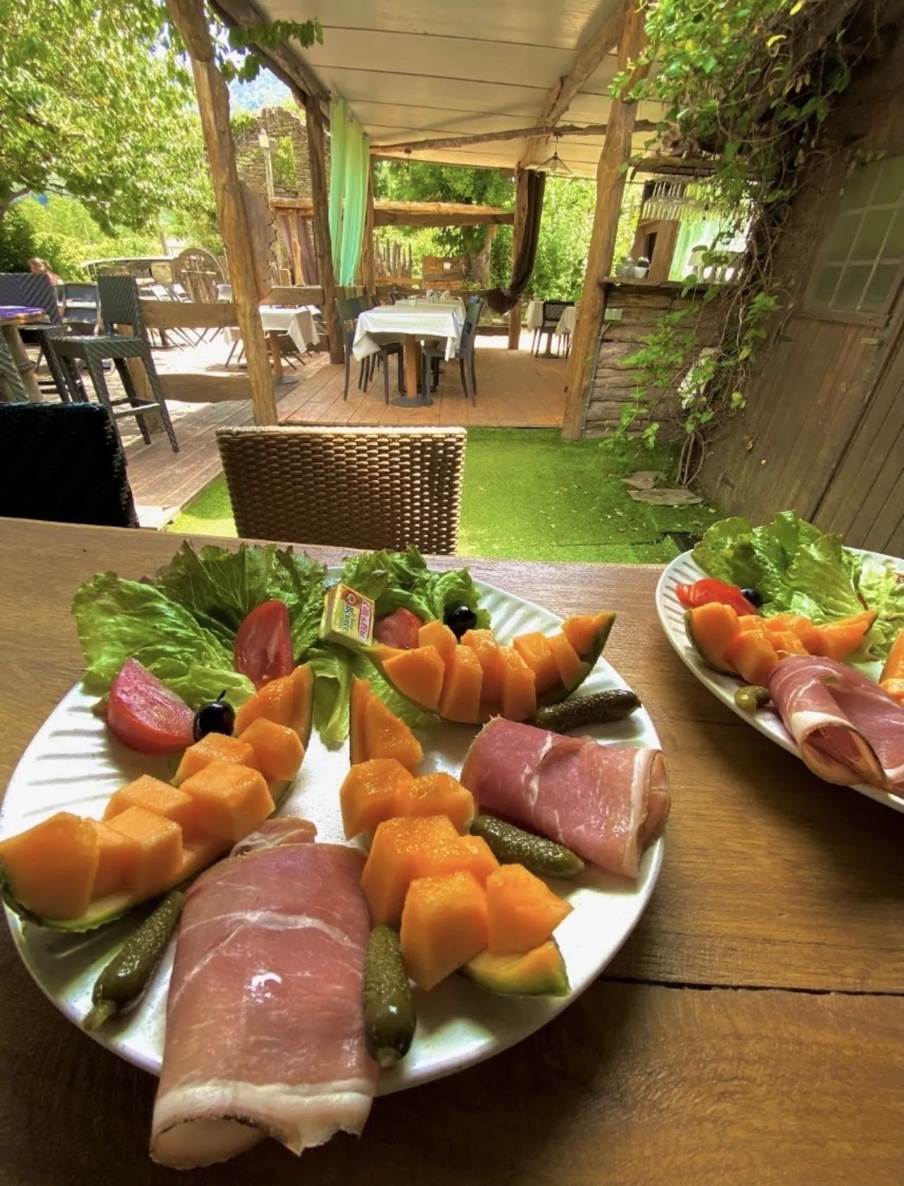Assiette de jambon sec, melon et cornichons en terrasse