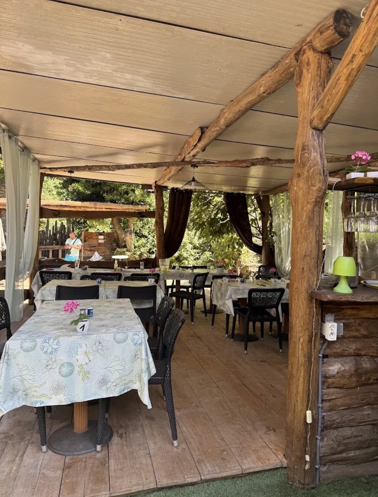 La salle du restaurant sous la pergola en bois, tables dressées